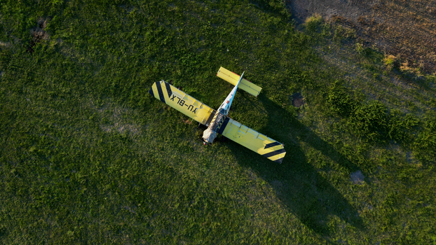 Serbia 03 September 2023 Aerial view of a yellow and black light aircraft parked on a grassy field during the golden hour.