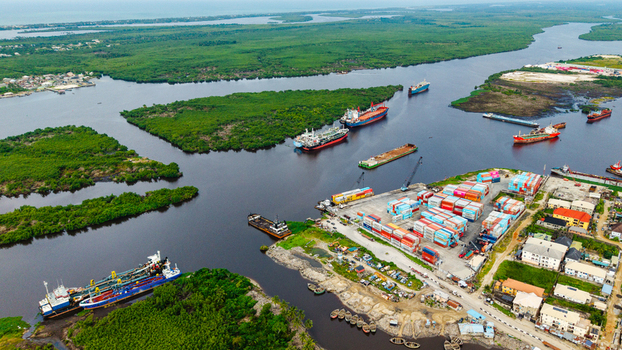 Aerial view of the busy port and container terminal in Satellite Town featuring cargo ships stacked shipping containers and lush mangrove vegetation in Lagos Lagos Nigeria.