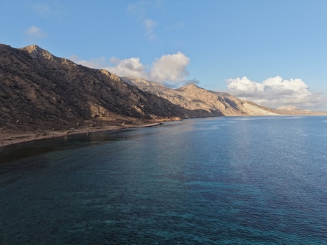 Aerial view of the rugged sun kissed mountains meet the turquoise waters along the coast Dhi Hamri Socotra Yemen. Aerial view of the rugged sun kissed mountains meet the turquoise waters along the coast Dhi Hamri Socotra Yemen.