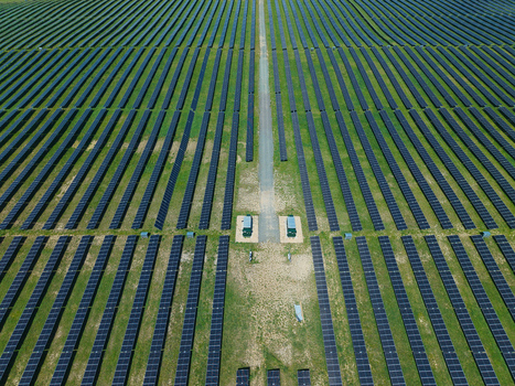 Aerial view of a large solar farm with rows of photovoltaic panels on green grass and a central access road Little Irchester England United Kingdom. Aerial view of a large solar farm with rows of photovoltaic panels on green grass and a central access road Little Irchester England United Kingdom.