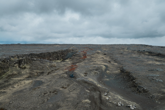 Aerial view of the rugged volcanic landscape near Sandfellshaed Viewpoint with a dirt road winding through dark lava fields under a cloudy sky in Keflavik Reykjanesbaer Iceland.