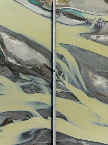Aerial view of glacial rivers carving paths through volcanic black sands under a bridge Iceland Iceland. Aerial view of glacial rivers carving paths through volcanic black sands under a bridge Iceland Iceland.