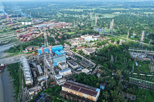 Aerial view of the power plant along the Karnaphuli River with industrial buildings cooling towers and electrical transmission lines in Chattogram Chittagong Division Bangladesh.