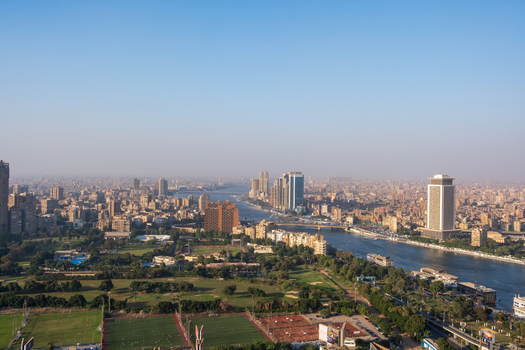 View of the Nile River snakes through the sprawling cityscape reflecting the clear sky above the buildings in Zamalek Cairo Governorate Egypt. View of the Nile River snakes through the sprawling cityscape reflecting the clear sky above the buildings in Zamalek Cairo Governorate Egypt.