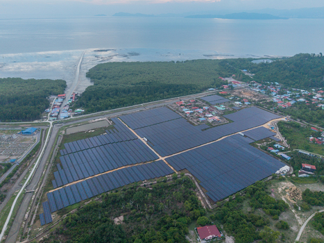 Aerial view of large scale solar photovoltaic power plant with rows of solar panels situated near a coastal village and lush greenery in Central Seberang Perai Penang Malaysia. Aerial view of large scale solar photovoltaic power plant with rows of solar panels situated near a coastal village and lush greenery in Central Seberang Perai Penang Malaysia.