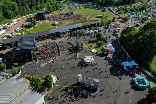 Geiselwind Germany 21 June 2025 Aerial view of Eventzentrum Strohofer Geiselwind musichall with festival stages large crowds of people and white tents under a clear sky. Geiselwind Germany 21 June 2025 Aerial view of Eventzentrum Strohofer Geiselwind musichall with festival stages large crowds of people and white tents under a clear sky.