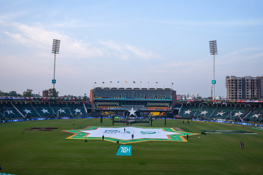 Lahore Pakistan 17 February 2024 View of Gaddafi Stadium with a large star shaped logo on the cricket pitch stadium seating and floodlights under a clear sky.