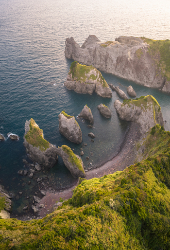 Aerial view of Koganezaki featuring a rugged coastline with sea stacks and a natural rock arch surrounded by lush green cliffs in Izu Shizuoka Japan. Aerial view of Koganezaki featuring a rugged coastline with sea stacks and a natural rock arch surrounded by lush green cliffs in Izu Shizuoka Japan.