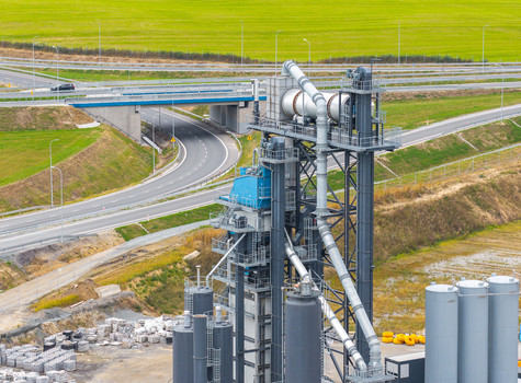 Aerial view of asphalt mixing plant with industrial silos and machinery located next to an expressway and green fields Pomeranian Voivodeshi Poland.