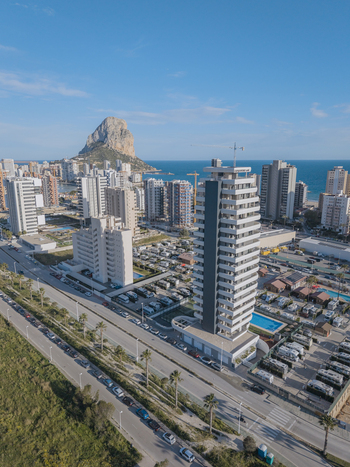 Aerial view of the Penon de Ifach rock formation rising above the coastal skyline modern high rise apartment buildings and a caravan park in Calp Valencian Community Spain. Aerial view of the Penon de Ifach rock formation rising above the coastal skyline modern high rise apartment buildings and a caravan park in Calp Valencian Community Spain.