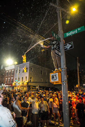 Williamsburg Brooklyn New York USA 14 June 2026 View of a fan celebrating on a street pole with champagne spray amidst a crowd during the Knicks NBA championship victory. Williamsburg Brooklyn New York USA 14 June 2026 View of a fan celebrating on a street pole with champagne spray amidst a crowd during the Knicks NBA championship victory.