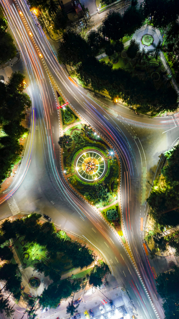 Aerial view of Monumen Bambu Runcing at night with light trails from traffic on the surrounding roads lush trees and urban infrastructure in Kecamatan Genteng Jawa Timur Indonesia. Aerial view of Monumen Bambu Runcing at night with light trails from traffic on the surrounding roads lush trees and urban infrastructure in Kecamatan Genteng Jawa Timur Indonesia.
