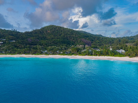 Aerial view of turquoise waters meet the pristine white sands fringed by lush green hills under a cloudy sky Quatre Bornes Seychelles. Aerial view of turquoise waters meet the pristine white sands fringed by lush green hills under a cloudy sky Quatre Bornes Seychelles.