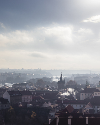 View of the historic rooftops and towers of the old town under a hazy sky with the Vltava River in the distance Prague Prague Czechia. View of the historic rooftops and towers of the old town under a hazy sky with the Vltava River in the distance Prague Prague Czechia.