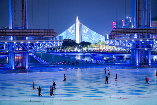 Guangzhou Guangdong Province China 24 February 2024 View of the illuminated Haixinsha Asian Games Park at night with people walking across the blue lit plaza. Guangzhou Guangdong Province China 24 February 2024 View of the illuminated Haixinsha Asian Games Park at night with people walking across the blue lit plaza.