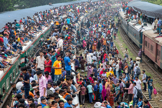 Dhaka Bangladesh 15 June 2018 View of a massive crowd of people sitting on the roofs and hanging off the sides of overcrowded trains at Airport Railway Station. Dhaka Bangladesh 15 June 2018 View of a massive crowd of people sitting on the roofs and hanging off the sides of overcrowded trains at Airport Railway Station.