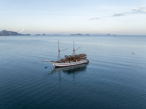 Aerial view of a traditional wooden Phinisi boat sailing on the calm blue waters near Labuan Bajo Komodo East Nusa Tenggara Indonesia. Aerial view of a traditional wooden Phinisi boat sailing on the calm blue waters near Labuan Bajo Komodo East Nusa Tenggara Indonesia.