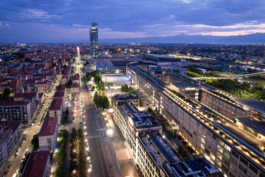 Aerial view of the historic Lingotto building and the modern urban skyline with illuminated streets and the Alps in the background at twilight in Turin Piedmont Italy. Aerial view of the historic Lingotto building and the modern urban skyline with illuminated streets and the Alps in the background at twilight in Turin Piedmont Italy.