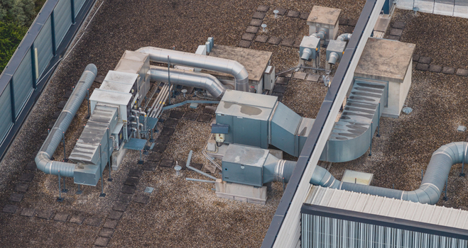Aerial view of a modern commercial building roof featuring industrial HVAC ventilation systems metallic ductwork and gravel surfacing in Valence Auvergne Rhone Alpes France.