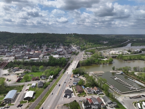 Aerial view of the small town landscape featuring a bridge crossing the river a marina with boat slips and lush green hills under a cloudy sky in Aurora Indiana United States. Aerial view of the small town landscape featuring a bridge crossing the river a marina with boat slips and lush green hills under a cloudy sky in Aurora Indiana United States.