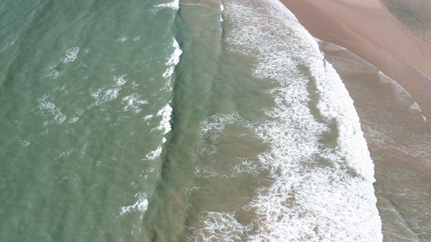 Aerial view of Bantham Beach with waves crashing on the sandy shore and white foam on the turquoise water Kingsbridge Devon United Kingdom. Aerial view of Bantham Beach with waves crashing on the sandy shore and white foam on the turquoise water Kingsbridge Devon United Kingdom.