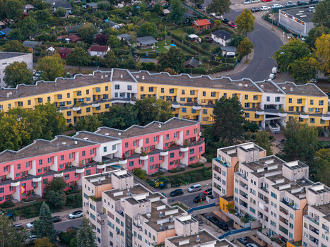 Aerial view of High Deck Siedlung with its distinctive yellow and pink residential apartment buildings surrounded by green spaces trees and urban streets in Berlin Berlin Germany. Aerial view of High Deck Siedlung with its distinctive yellow and pink residential apartment buildings surrounded by green spaces trees and urban streets in Berlin Berlin Germany.