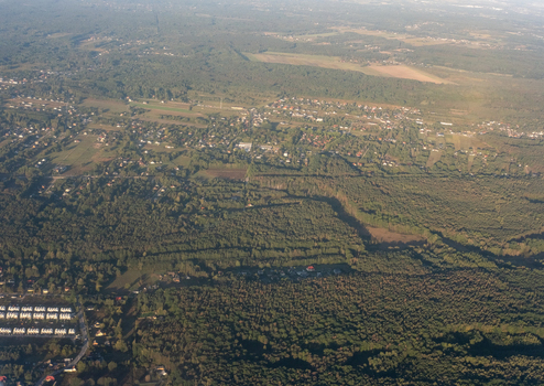Aerial view of a sprawling green canopy interspersed with pockets of buildings creating a mosaic of nature and urban development Masovian Voivodeship Poland. Aerial view of a sprawling green canopy interspersed with pockets of buildings creating a mosaic of nature and urban development Masovian Voivodeship Poland.