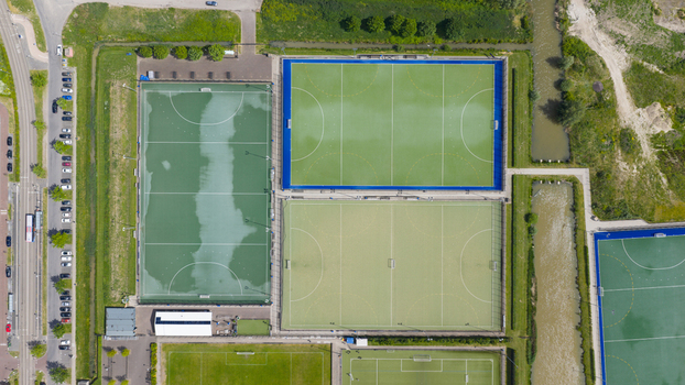 Aerial view of H.C. Rijnvliet hockey fields featuring green and blue artificial turf pitches a parking lot and surrounding greenery in Utrecht Utrecht Netherlands.