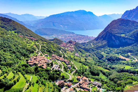 Aerial view of the historic stone village of Canale di Tenno nestled in lush green hills with Lake Garda in the background Ville del Monte Trentino Alto Adige Italy. Aerial view of the historic stone village of Canale di Tenno nestled in lush green hills with Lake Garda in the background Ville del Monte Trentino Alto Adige Italy.