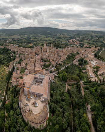 Aerial view of the medieval towers and historic stone buildings surrounded by lush rolling hills in San Gimignano Tuscany Italy. Aerial view of the medieval towers and historic stone buildings surrounded by lush rolling hills in San Gimignano Tuscany Italy.