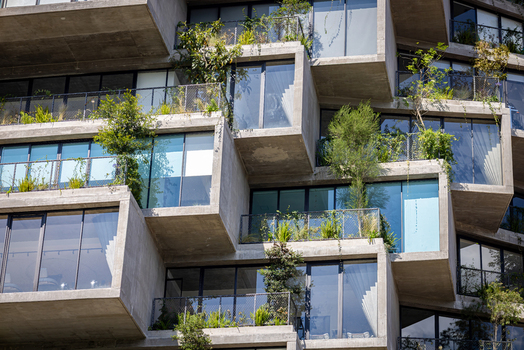 View of a modern residential building featuring cantilevered concrete balconies with lush green vegetation and large glass windows in Quito Pichincha Ecuador.