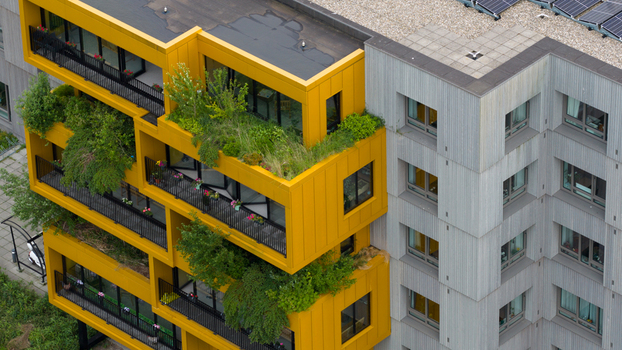 Aerial view of modern apartment buildings with vibrant yellow balconies filled with lush green plants and trees Almere Flevoland Netherlands. Aerial view of modern apartment buildings with vibrant yellow balconies filled with lush green plants and trees Almere Flevoland Netherlands.
