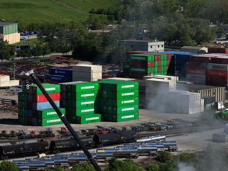 Cincinnati United States 19 April 2026 Aerial view of stacked shipping containers and industrial rail cars in a logistics yard under bright daylight.
