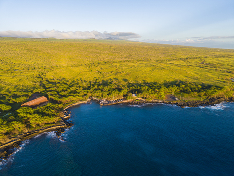 Aerial view of Mahukona Beach Park with its rocky coastline blue ocean waters and lush green hills under a clear sky Waimea Hawaii United States.