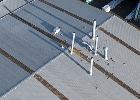 Melbourne Australia 22 September 2026 Aerial view of the industrial roof of a factory in Kilsyth featuring metal vents and long shadows cast across the corrugated surface. Melbourne Australia 22 September 2026 Aerial view of the industrial roof of a factory in Kilsyth featuring metal vents and long shadows cast across the corrugated surface.