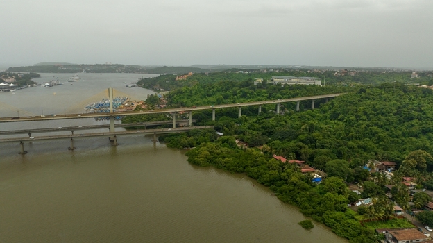 Aerial view of the Atal Setu bridge spanning the Mandovi River surrounded by lush green vegetation and urban development in Panaji Goa India.