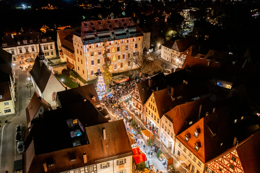 Forchheim Germany 20 December 2025 Aerial view of the Weihnachtsmarkt Forchheim at the Kaiserpfalz with illuminated stalls and historic timber framed buildings at night.