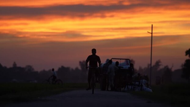 View of a person cycling on a rural road at sunset Bangladesh. View of a person cycling on a rural road at sunset Bangladesh.