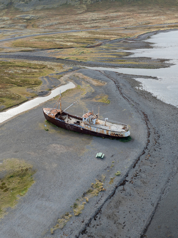 Aerial view of a rusted shipwreck resting on the stark dark sands where the sea meets the Icelandic coast Westfjords Iceland. Aerial view of a rusted shipwreck resting on the stark dark sands where the sea meets the Icelandic coast Westfjords Iceland.
