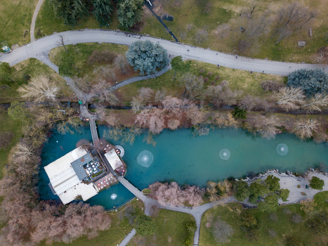 Aerial view of a turquoise pond with fountains and a lakeside building surrounded by walking paths and lush trees in a public park Bologna Emilia Romagna Italy. Aerial view of a turquoise pond with fountains and a lakeside building surrounded by walking paths and lush trees in a public park Bologna Emilia Romagna Italy.