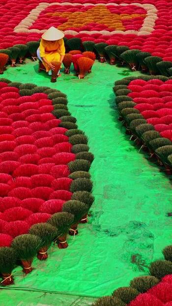 View of a worker among vibrant incense bundles Vietnam.
