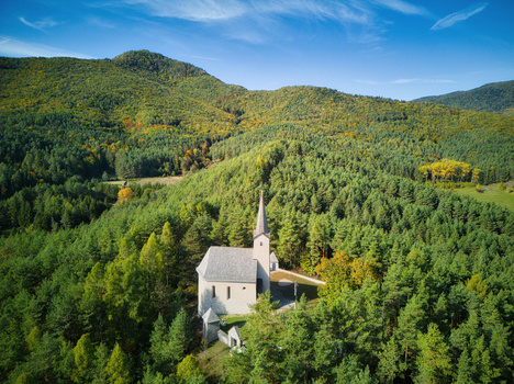 Aerial view of a church nestled within a vibrant green forest a stark contrast against the clear blue sky Calvary Zilina Region Slovakia. Aerial view of a church nestled within a vibrant green forest a stark contrast against the clear blue sky Calvary Zilina Region Slovakia.