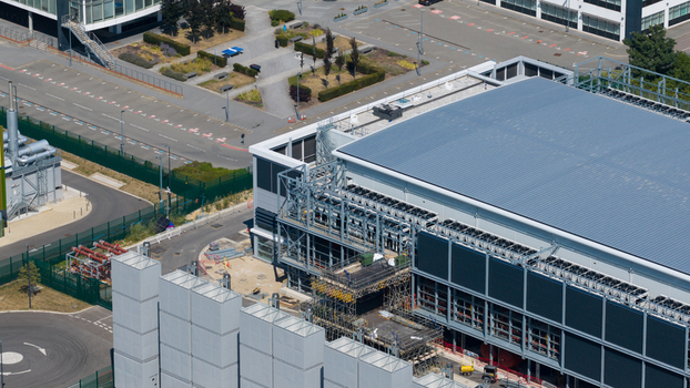 Aerial view of the Kao Data facility featuring modern industrial architecture with rooftop cooling units and surrounding infrastructure in Harlow England United Kingdom. Aerial view of the Kao Data facility featuring modern industrial architecture with rooftop cooling units and surrounding infrastructure in Harlow England United Kingdom.