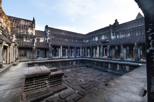 View of Angkor Wat featuring ancient stone architecture intricate carvings and a central courtyard under a clear blue sky in Krong Siem Reap Siem Reap Province Cambodia.