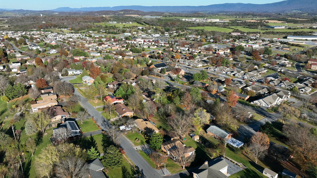 Aerial view of a suburban residential neighborhood featuring single family homes tree lined streets with autumn foliage and distant mountains in Harrisonburg Virginia United States.