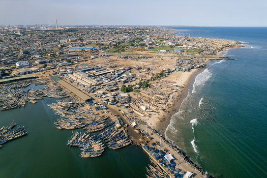 Aerial view of the vibrant harbor teeming with fishing boats contrasting with the sandy beach and the bustling city beyond Tema Ghana. Aerial view of the vibrant harbor teeming with fishing boats contrasting with the sandy beach and the bustling city beyond Tema Ghana.