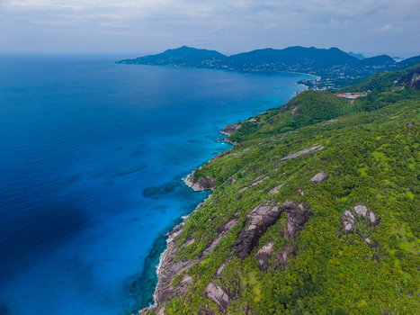 Aerial view of the coastline where lush green hills meet the deep blue sea in a stunning display of natural beauty Montagne Jasmin Mahe Island Seychelles. Aerial view of the coastline where lush green hills meet the deep blue sea in a stunning display of natural beauty Montagne Jasmin Mahe Island Seychelles.