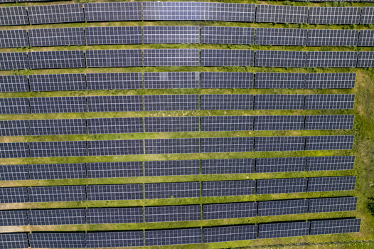 Aerial view of a large solar panel farm with rows of photovoltaic panels installed on green grass in Guanaja Bay Islands Department Honduras.