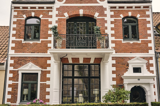 Viborg Denmark 07 August 2026 View of the neoclassical early 20th century facade of a brick building featuring white trim a wrought iron balcony and large windows. Viborg Denmark 07 August 2026 View of the neoclassical early 20th century facade of a brick building featuring white trim a wrought iron balcony and large windows.