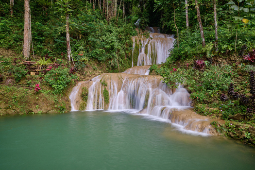 View of Air Terjun Kuncung Mas waterfall cascading over tiers into a turquoise pool surrounded by lush tropical forest in Kecamatan Girimulyo Daerah Istimewa Yogya Indonesia. View of Air Terjun Kuncung Mas waterfall cascading over tiers into a turquoise pool surrounded by lush tropical forest in Kecamatan Girimulyo Daerah Istimewa Yogya Indonesia.